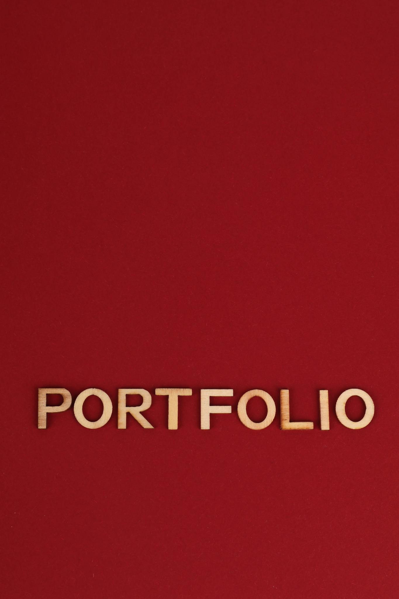 Wooden text spelling 'PORTFOLIO' on a bold red background, ideal for design and business themes.